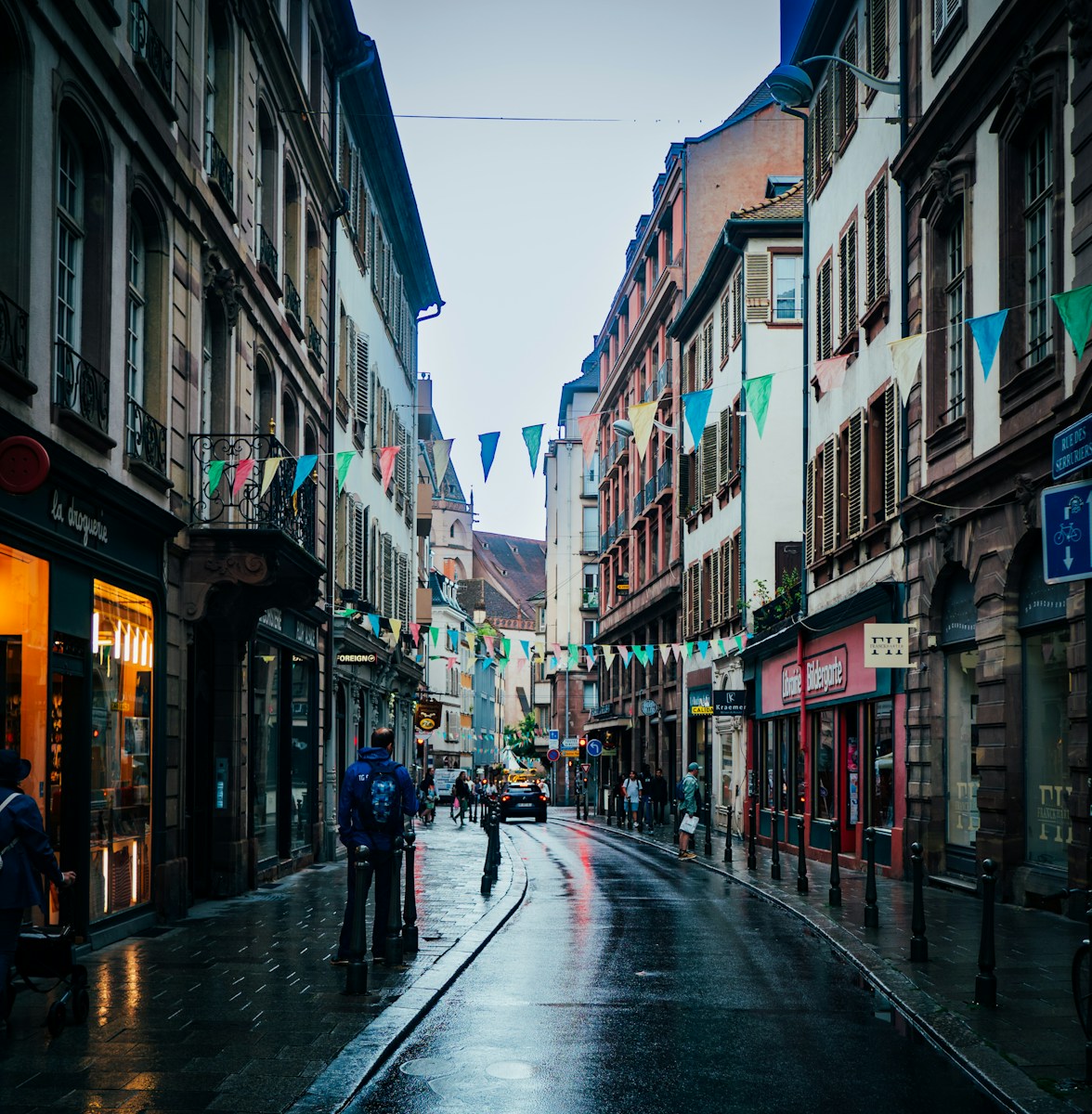 a wet city street with people walking on it